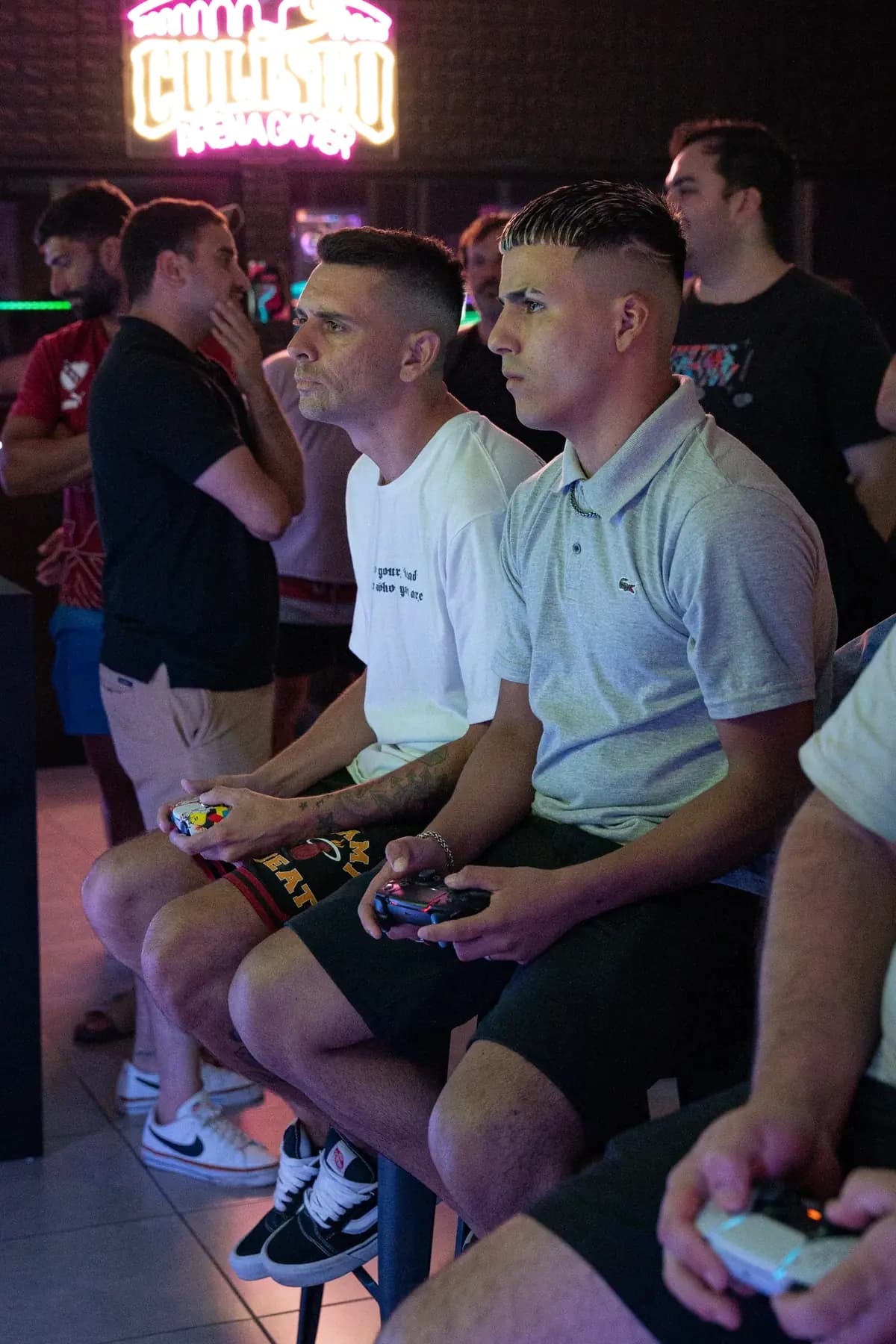 Dos jugadores con joystick en mano durante el torneo, con gente alrededor